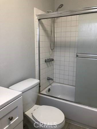 full bathroom with toilet, bath / shower combo with glass door, and vanity