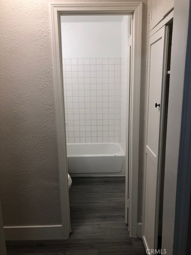 bathroom featuring tiled shower / bath, hardwood / wood-style floors, and toilet