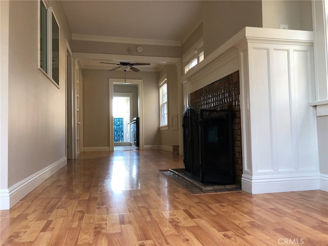 unfurnished living room with light hardwood / wood-style floors, ornamental molding, and ceiling fan