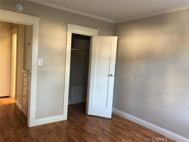 unfurnished bedroom featuring a closet, ornamental molding, and dark hardwood / wood-style flooring