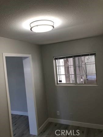 unfurnished room featuring wood-type flooring and a textured ceiling