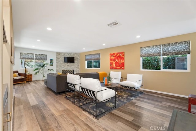 living room featuring plenty of natural light, hardwood / wood-style floors, and a stone fireplace