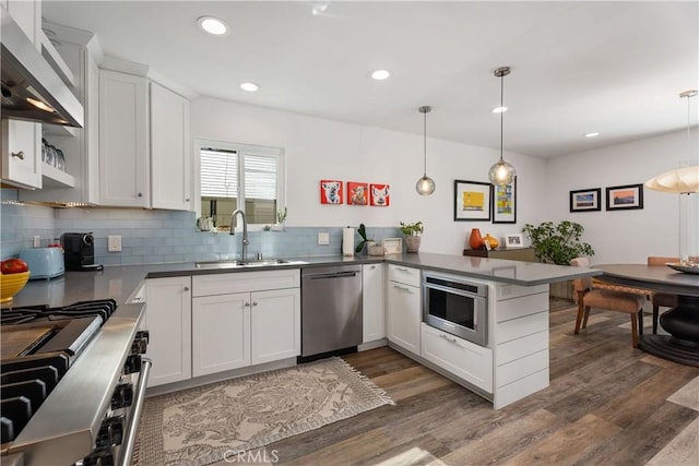 kitchen featuring white cabinetry, kitchen peninsula, appliances with stainless steel finishes, decorative light fixtures, and sink