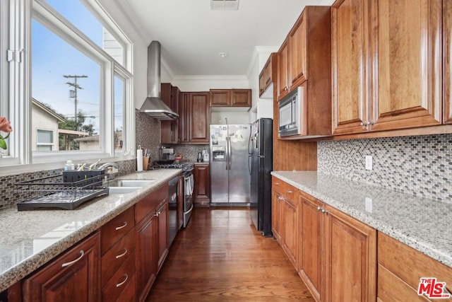 kitchen with dark hardwood / wood-style floors, light stone counters, wall chimney range hood, and appliances with stainless steel finishes