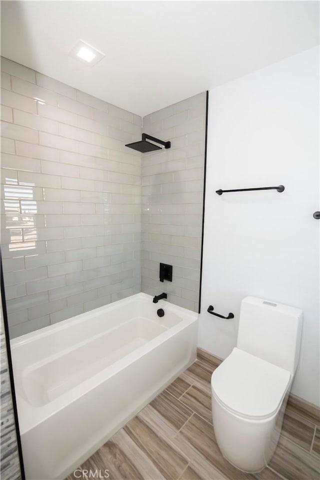 bathroom with toilet and tiled shower / bath