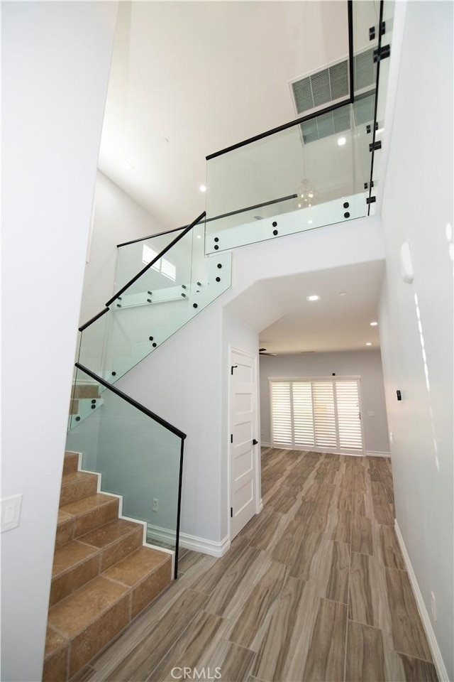 staircase with wood-type flooring and a high ceiling