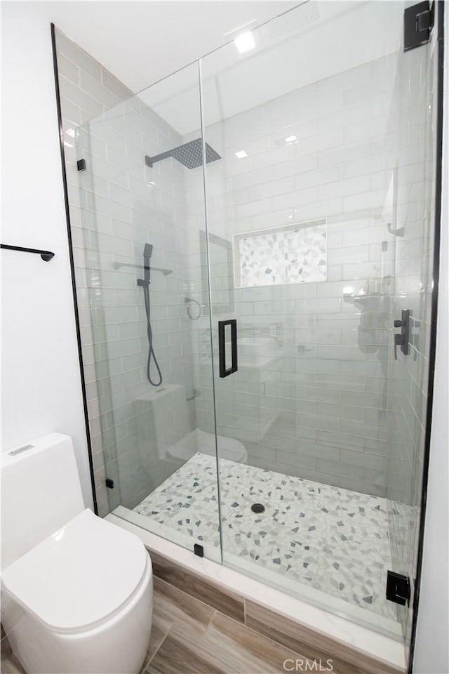 bathroom with a shower with shower door and toilet