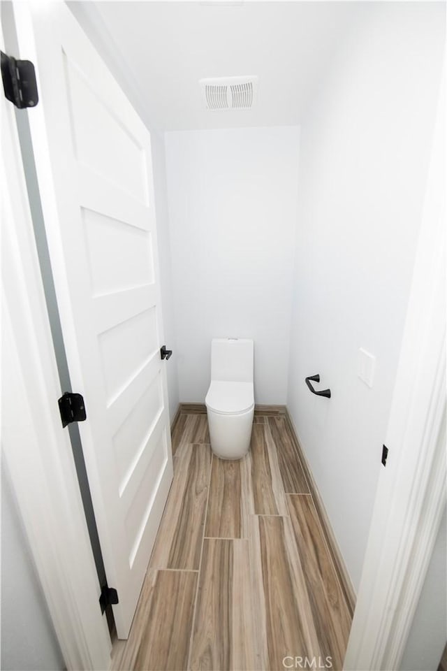 bathroom featuring hardwood / wood-style flooring and toilet