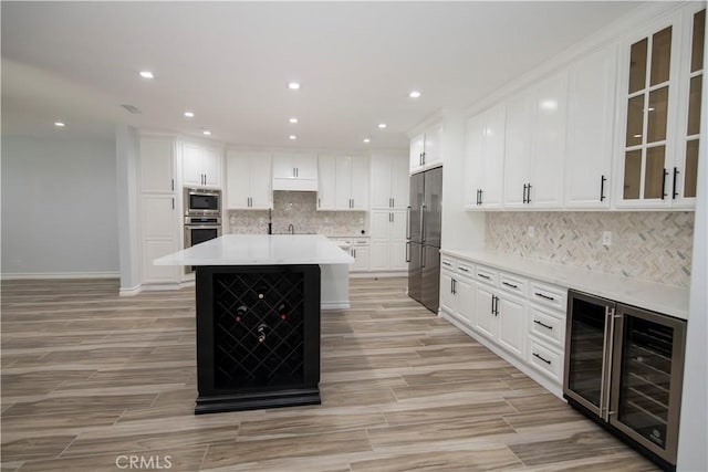 kitchen with a center island, wine cooler, decorative backsplash, white cabinets, and appliances with stainless steel finishes