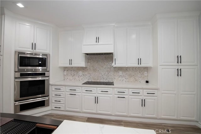 kitchen featuring appliances with stainless steel finishes, backsplash, light hardwood / wood-style flooring, and white cabinetry