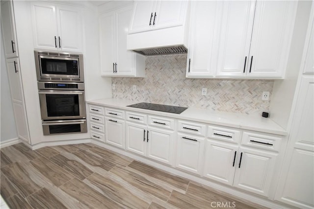 27404 Outrigger Ln, Helendale, CA 92342 - kitchen with black electric cooktop, stainless steel microwave, backsplash, and white cabinets