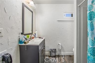 bathroom featuring wood-type flooring, vanity, toilet, and curtained shower