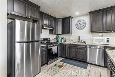 kitchen with sink, a textured ceiling, tasteful backsplash, dark brown cabinetry, and stainless steel appliances