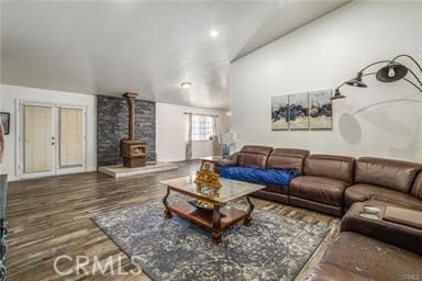 living room featuring french doors, vaulted ceiling, dark hardwood / wood-style floors, and a wood stove