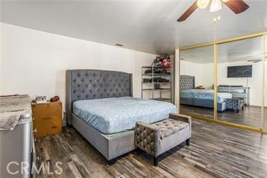 bedroom with ceiling fan, dark wood-type flooring, and a closet