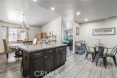 kitchen featuring pendant lighting, a breakfast bar, a center island, light stone countertops, and a notable chandelier