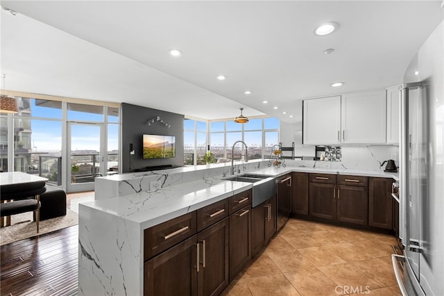 kitchen featuring white cabinets, light stone counters, stainless steel appliances, a wall of windows, and sink