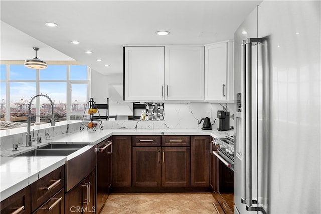 kitchen with appliances with stainless steel finishes, light tile patterned flooring, white cabinetry, decorative light fixtures, and light stone counters