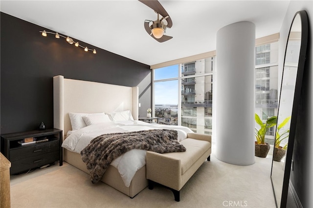 bedroom with light carpet and a wall of windows