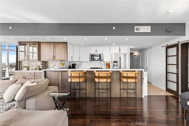 kitchen featuring a large island, dark hardwood / wood-style floors, appliances with stainless steel finishes, and a barn door