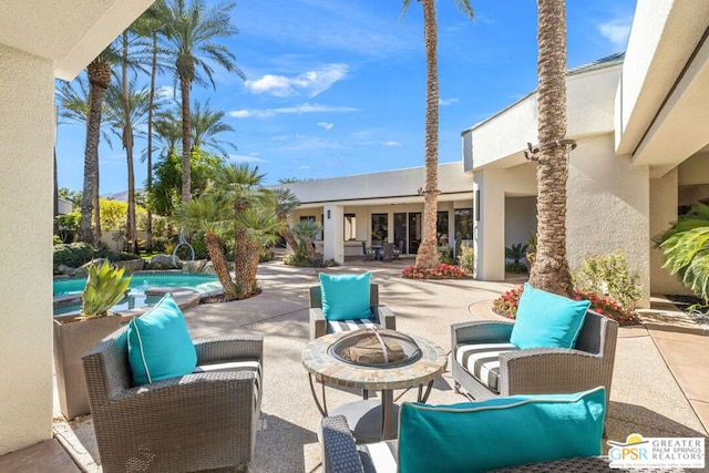 view of patio with pool water feature and a fire pit