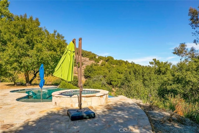 exterior space with an in ground hot tub and a patio