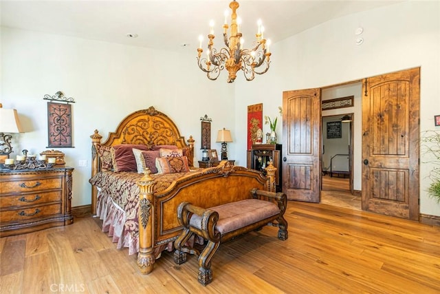 bedroom featuring lofted ceiling, a notable chandelier, and light wood-type flooring