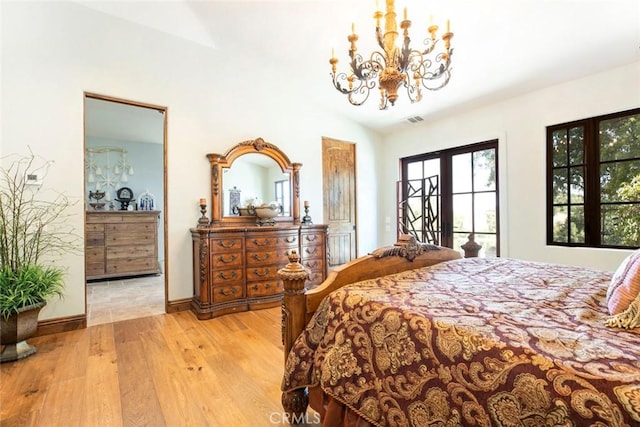 bedroom featuring a chandelier, french doors, vaulted ceiling, and light hardwood / wood-style flooring