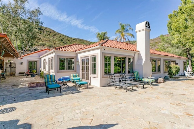 rear view of property with a patio area, a mountain view, and outdoor lounge area