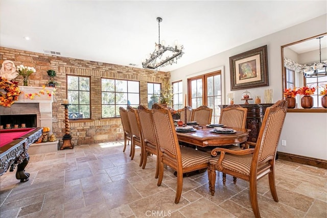 dining space with a fireplace, plenty of natural light, a notable chandelier, and billiards