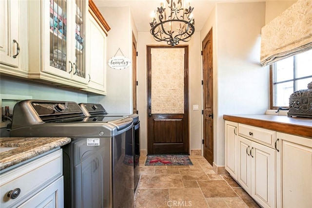 clothes washing area featuring cabinets, separate washer and dryer, and a chandelier