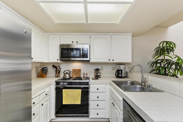 kitchen featuring white cabinetry, appliances with stainless steel finishes, sink, and tile counters