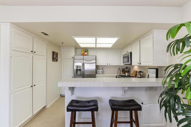 kitchen featuring white cabinetry, a breakfast bar area, stainless steel appliances, and kitchen peninsula