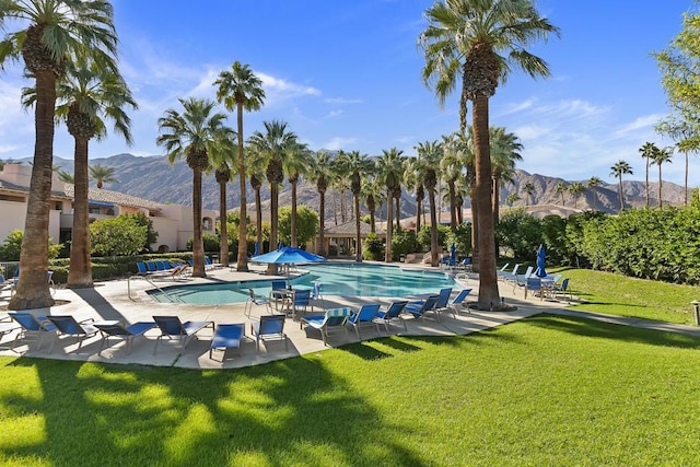 view of swimming pool with a mountain view, a patio area, and a lawn