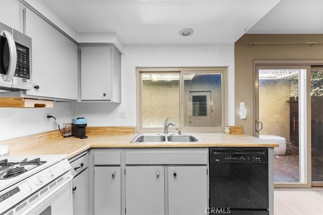 kitchen featuring stainless steel microwave, a sink, dishwasher, gas range gas stove, and plenty of natural light