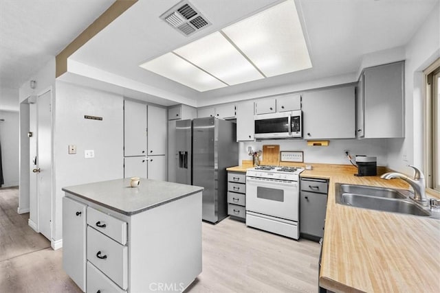 kitchen featuring visible vents, appliances with stainless steel finishes, light countertops, light wood-style floors, and a sink