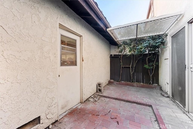 view of property exterior with fence, a patio, and stucco siding