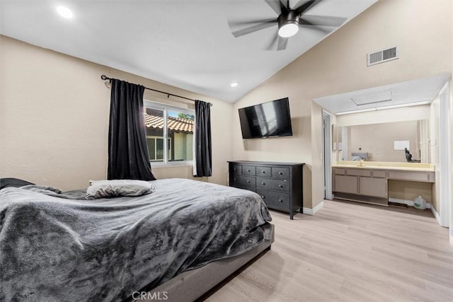 bedroom featuring light wood finished floors, visible vents, baseboards, lofted ceiling, and ensuite bath