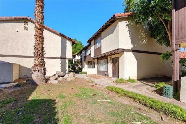 view of side of property featuring a tile roof and stucco siding