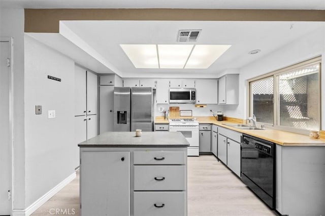 kitchen featuring visible vents, stainless steel appliances, a sink, and gray cabinetry