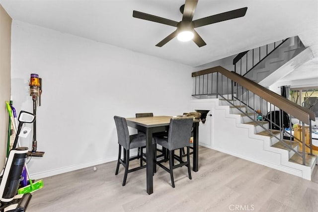 dining room with stairway, wood finished floors, a ceiling fan, and baseboards