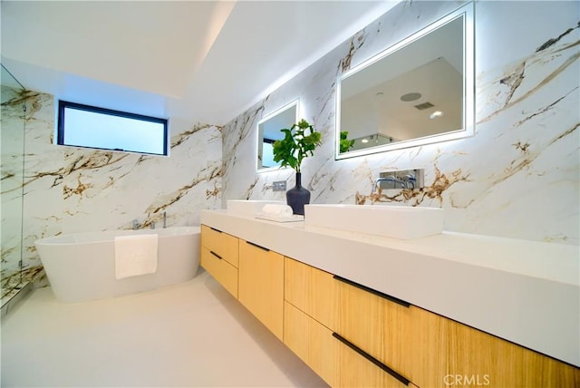 bathroom featuring double vanity, tile walls, a sink, and a soaking tub