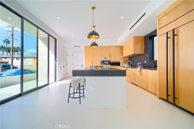 kitchen featuring pendant lighting, decorative backsplash, stainless steel oven, and light brown cabinetry