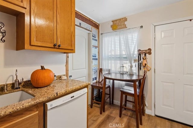 kitchen with light stone countertops, sink, white dishwasher, and light hardwood / wood-style flooring