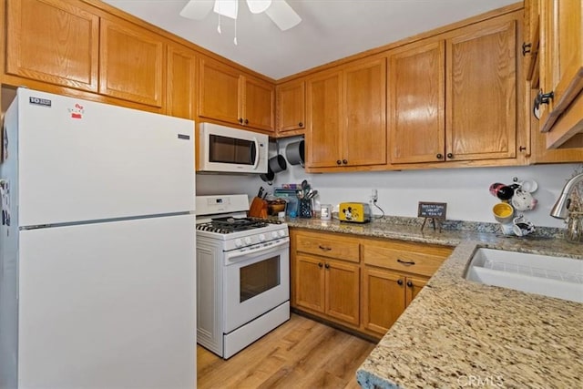 kitchen featuring light stone countertops, ceiling fan, sink, light hardwood / wood-style floors, and white appliances