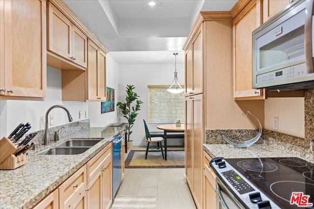 kitchen featuring hanging light fixtures, sink, light stone countertops, light brown cabinetry, and appliances with stainless steel finishes