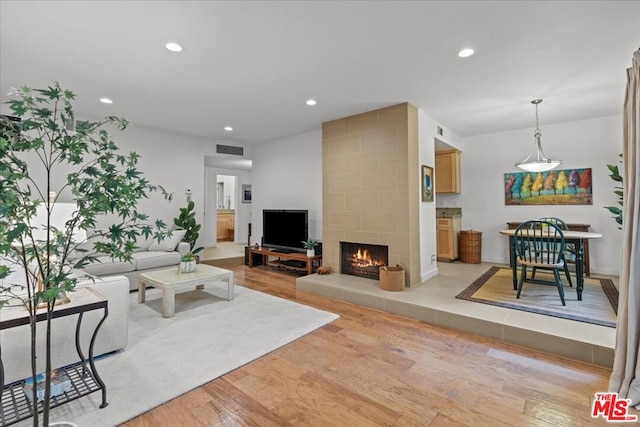 living room with a tile fireplace and light hardwood / wood-style floors