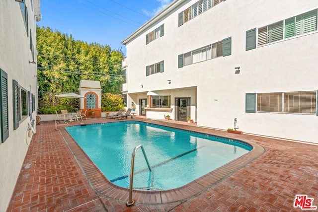 view of swimming pool featuring a fireplace and a patio