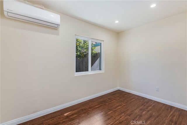 empty room featuring wood-type flooring and a wall mounted air conditioner