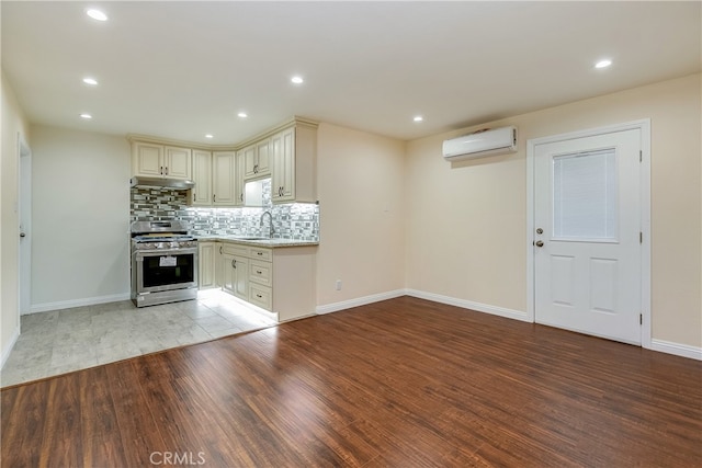 kitchen featuring light hardwood / wood-style flooring, stainless steel range oven, a wall mounted air conditioner, and cream cabinets